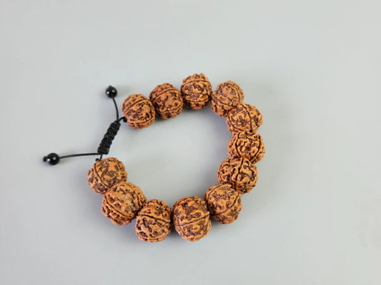 Handmade Rudraksha bead bracelet with adjustable black cord on a grey background
