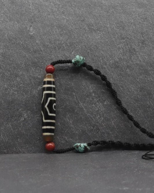 Handmade spiritual necklace with a carved black and white bead, red coral, and turquoise accents.