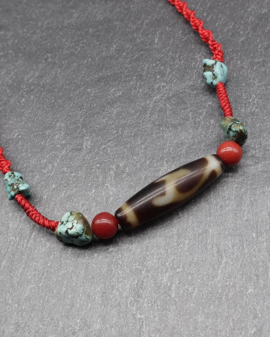 Handmade spiritual necklace with turquoise, red beads, and a brown carved stone on red cord