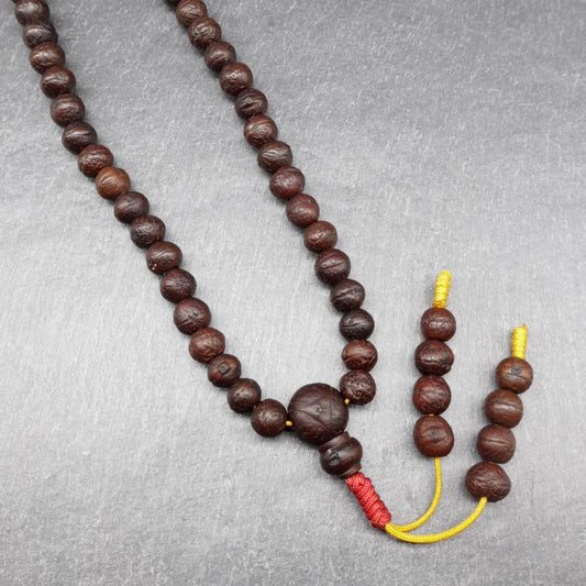 Authentic brown Rudraksha bead mala necklace with red tassel on a grey background