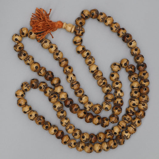 Traditional carved skull mala prayer beads with an orange tassel