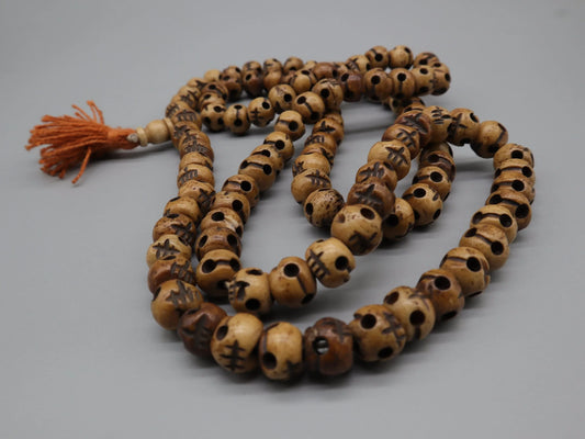 Handcrafted wooden prayer mala beads with sacred carvings and orange tassel