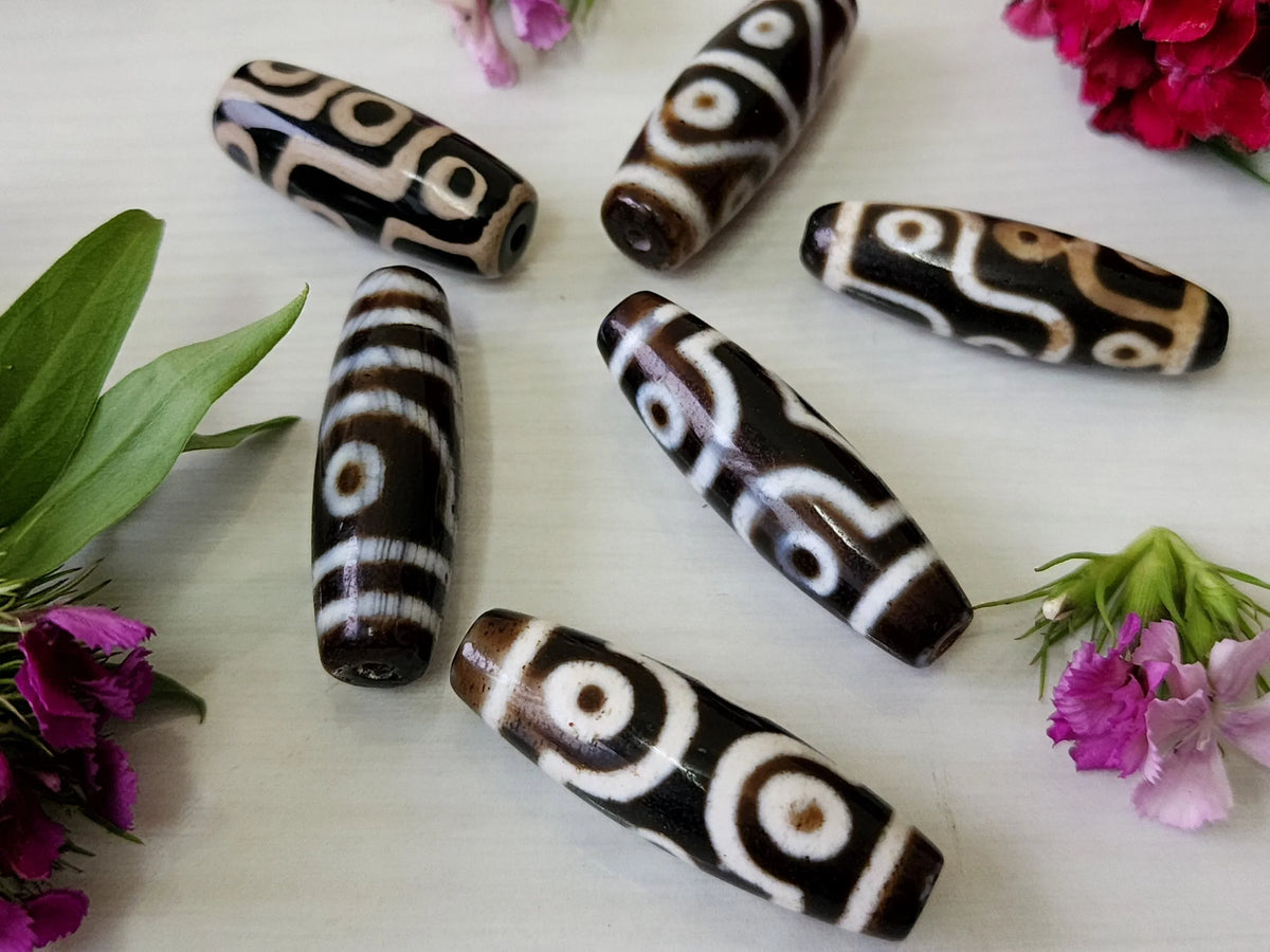 Handcrafted brown and white patterned cylindrical spiritual beads on a white background
