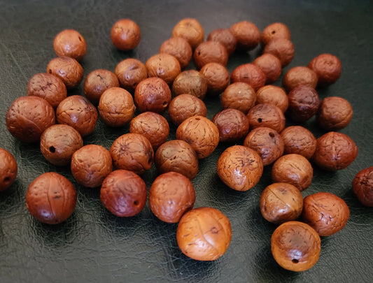 Authentic brown Rudraksha beads scattered on a dark textured surface