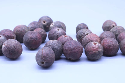Close-up of authentic purple-hued Rudraksha beads on a light background