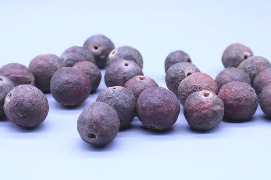 Close-up of authentic purple-hued Rudraksha beads on a light background
