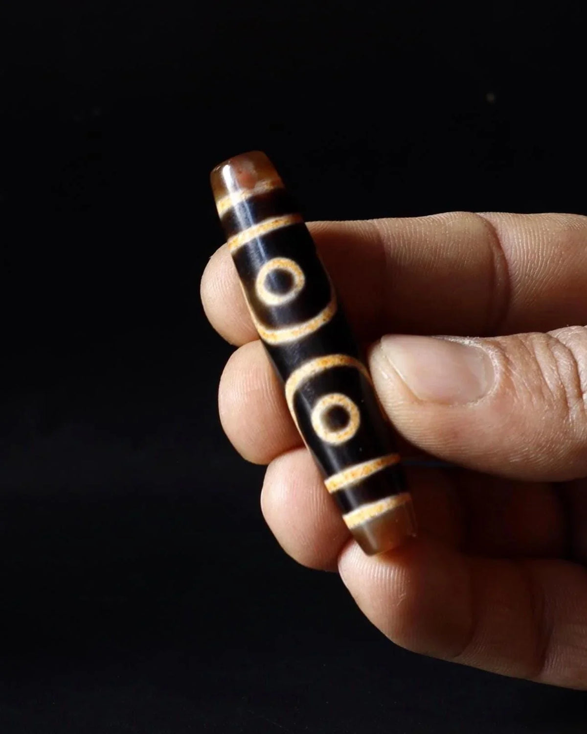 Hand-carved dark wood bead with gold circular patterns