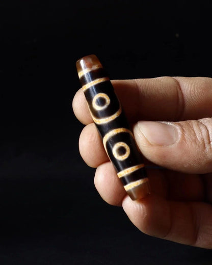 Hand-carved dark wood bead with gold circular patterns