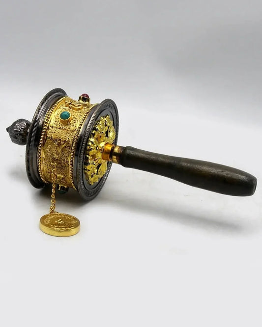 Handcrafted gold-plated Tibetan prayer wheel with a dark wooden handle