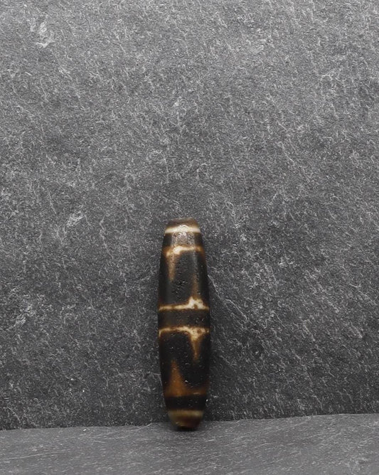 Handcrafted brown and white striped spiritual bead on a grey stone background