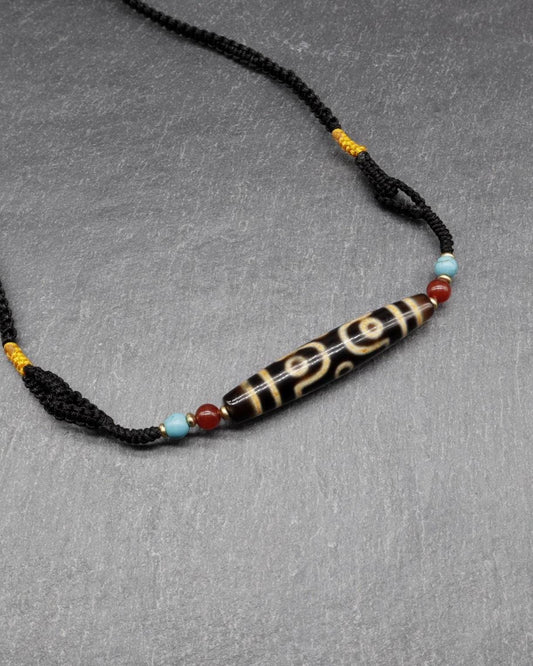 Handcrafted black cord necklace with a carved cylindrical bead and colorful accents