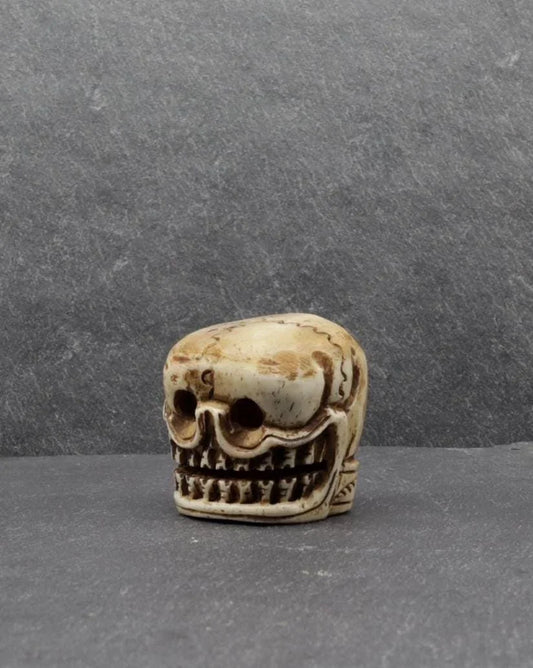 Hand-carved bone skull figurine with detailed teeth and facial features