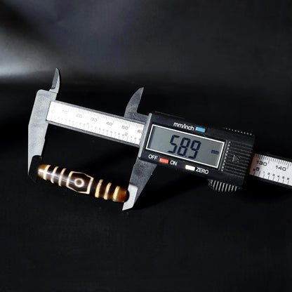 Digital caliper measuring a brown and cream patterned spiritual bead at 58.9mm