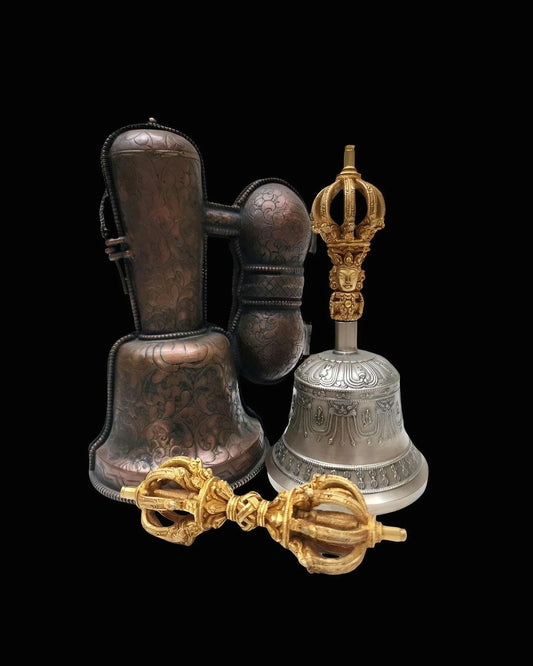 Three ornate traditional ritual bells in bronze, silver, and gold finishes.