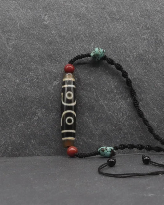 Handcrafted black cord bracelet with carved bone cylinder, red beads, and turquoise stones