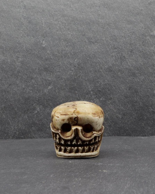 Hand-carved bone skull sculpture on a dark grey background
