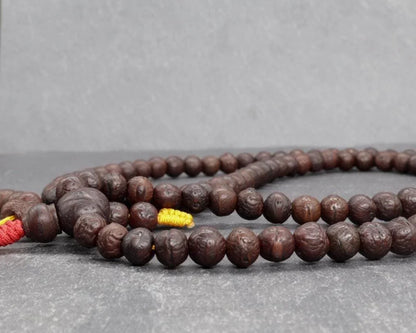Authentic brown Rudraksha prayer beads mala on a grey background