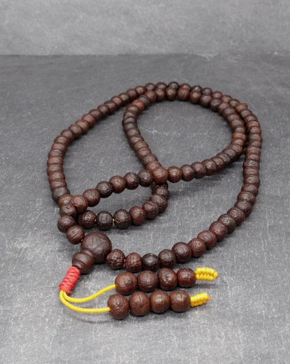 Authentic brown Rudraksha prayer mala beads on a gray background